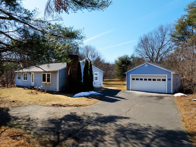 view of property exterior with an outdoor structure, a detached garage, and a chimney