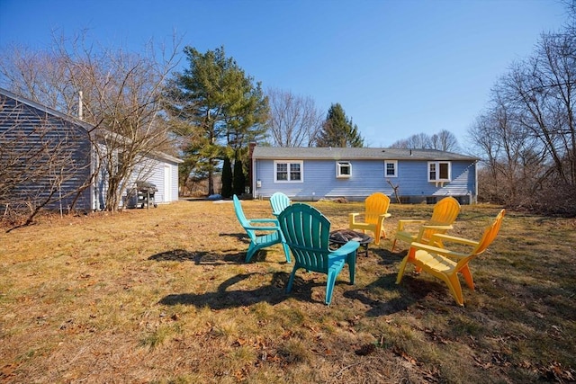 back of house featuring a fire pit and a lawn