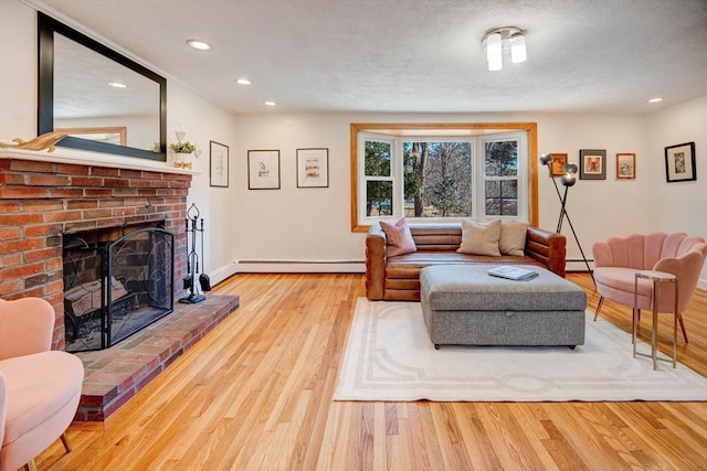 living area featuring a baseboard heating unit, baseboard heating, a fireplace, wood finished floors, and a textured ceiling