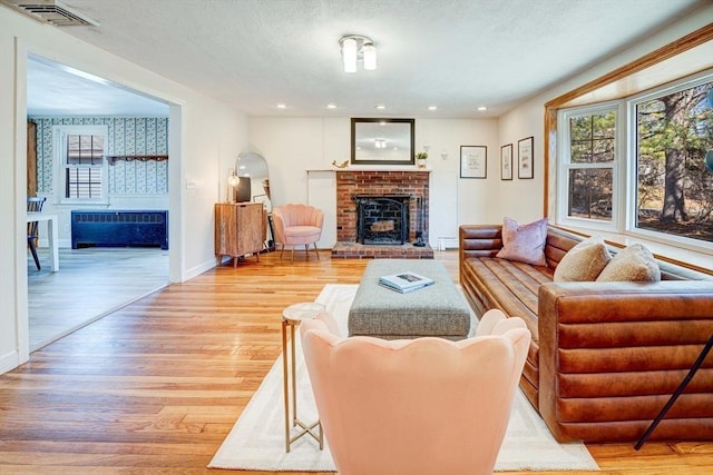 living area with visible vents, recessed lighting, a fireplace, a textured ceiling, and light wood-type flooring