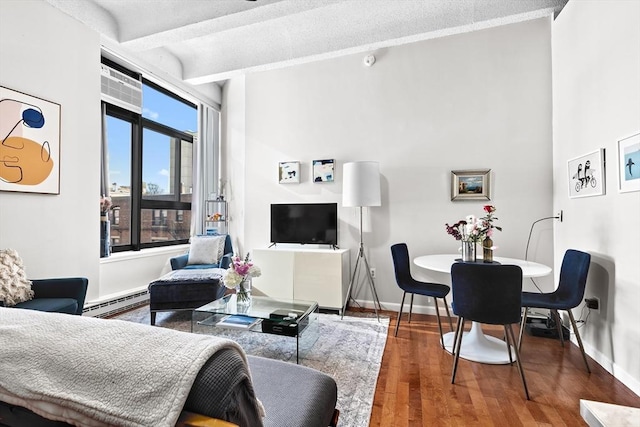 living room featuring baseboards, beam ceiling, a baseboard heating unit, and wood finished floors