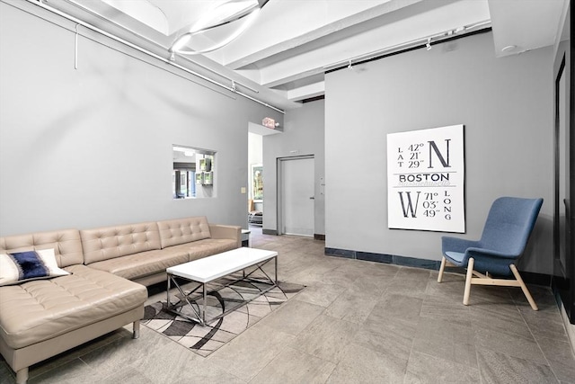 living room featuring a high ceiling and baseboards