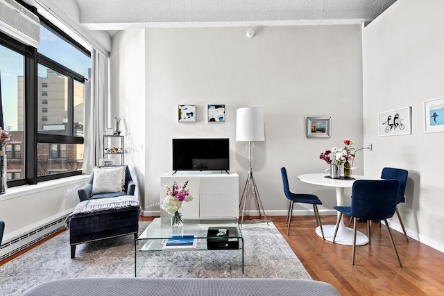 living area featuring a baseboard heating unit, wood finished floors, and baseboards