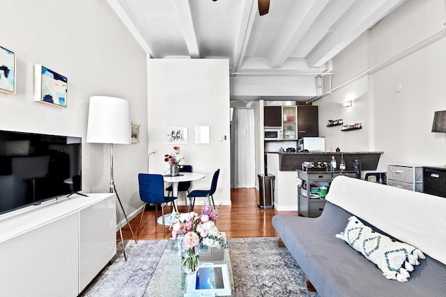 living room with wood finished floors, beam ceiling, and baseboards