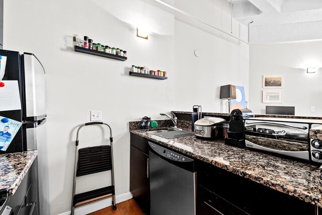 kitchen with black dishwasher, dark stone counters, wood finished floors, freestanding refrigerator, and open shelves