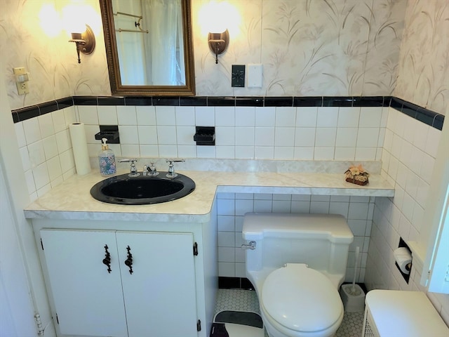 bathroom with tile walls, tile patterned flooring, vanity, and toilet