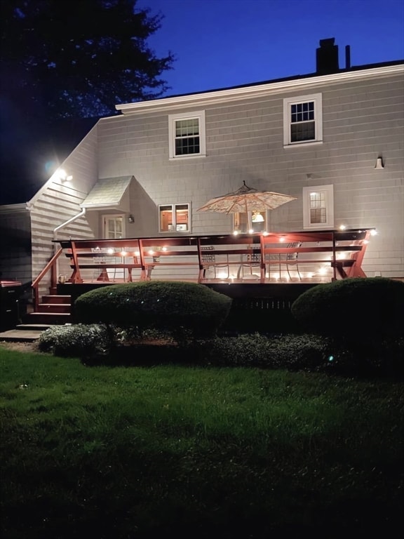 back house at twilight featuring a yard and a deck