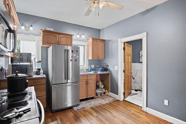 kitchen with wood-type flooring, baseboards, light countertops, a ceiling fan, and stainless steel appliances
