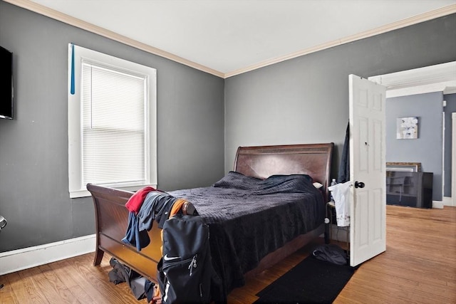 bedroom with baseboards, ornamental molding, and wood finished floors