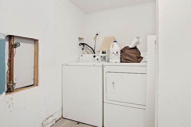clothes washing area featuring light wood-style floors, laundry area, and washer and dryer