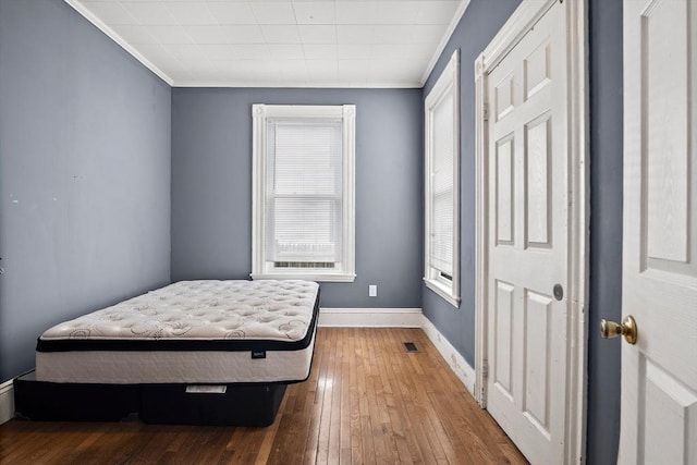 bedroom with crown molding, baseboards, visible vents, and hardwood / wood-style flooring