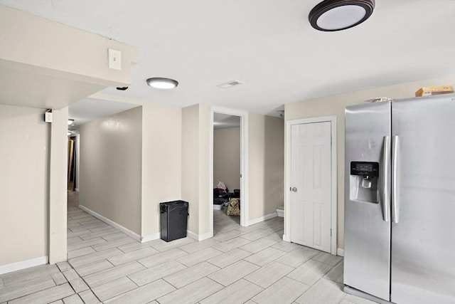 interior space with baseboards, wood tiled floor, stainless steel refrigerator with ice dispenser, and visible vents