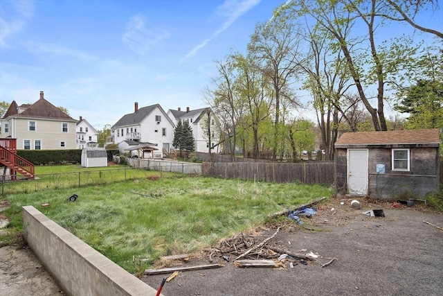 view of yard featuring fence, a residential view, an outdoor structure, and a shed
