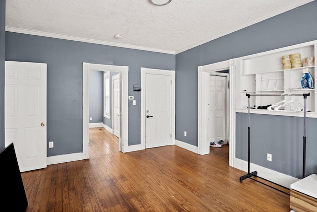 unfurnished bedroom with crown molding, a textured ceiling, baseboards, and hardwood / wood-style flooring
