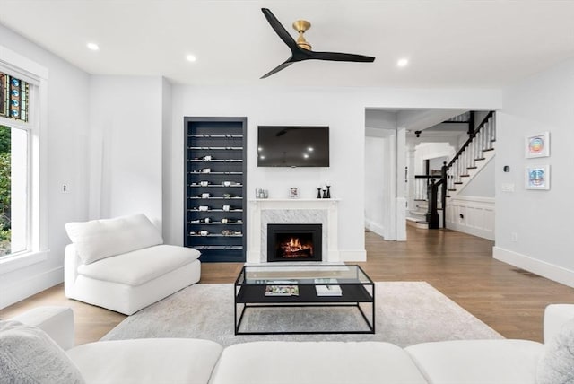 living room featuring wood finished floors, recessed lighting, a high end fireplace, ceiling fan, and stairs