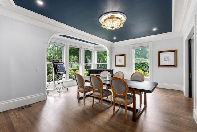 dining area featuring visible vents, ornamental molding, wood finished floors, arched walkways, and baseboards