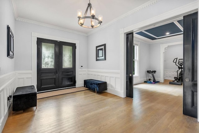 foyer entrance featuring wood finished floors, an inviting chandelier, and ornamental molding
