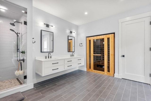 bathroom with double vanity, a shower stall, wood finished floors, and a sink