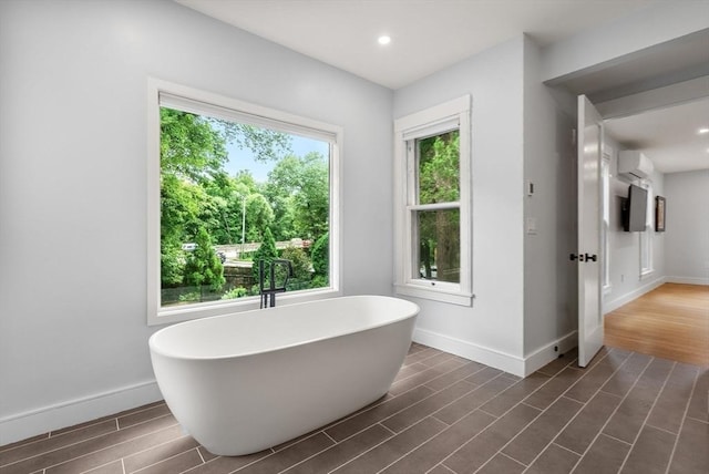 full bathroom featuring a freestanding bath, baseboards, and wood finished floors