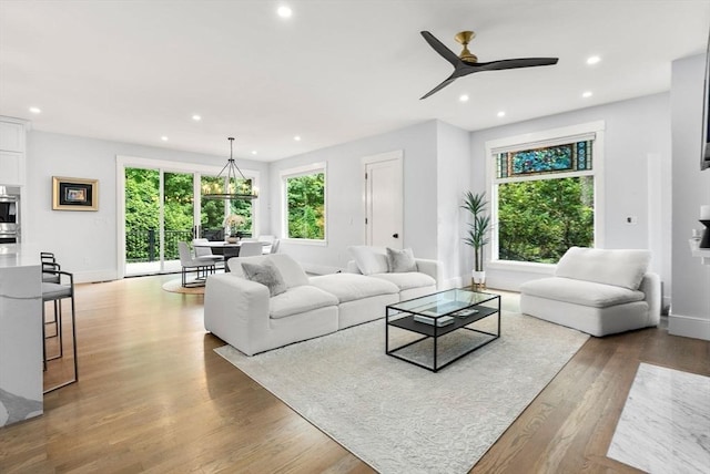 living area featuring ceiling fan with notable chandelier, recessed lighting, wood finished floors, and a wealth of natural light