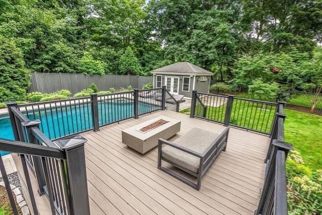deck featuring a fenced in pool, a storage structure, fence private yard, a lawn, and an outbuilding