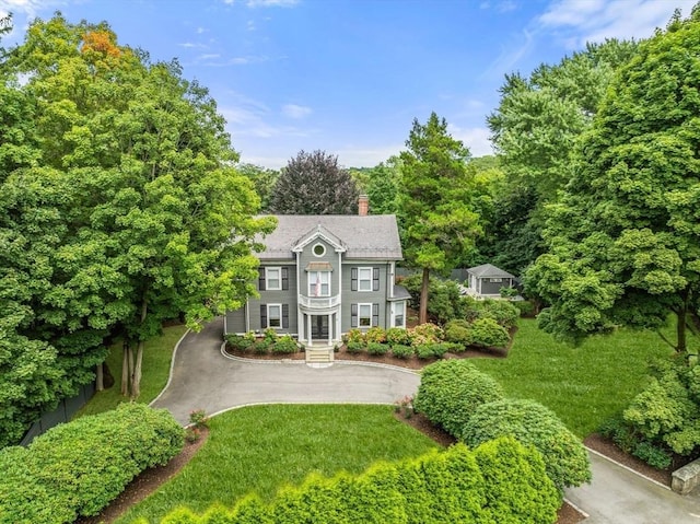 colonial inspired home featuring a front lawn and a chimney
