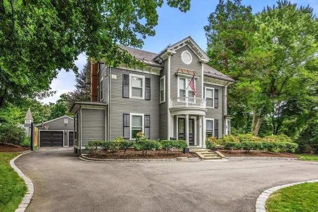 victorian house with an outdoor structure, a balcony, and a shingled roof