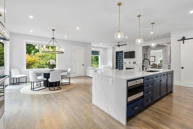 kitchen featuring light wood-style flooring, a sink, light countertops, decorative light fixtures, and open floor plan