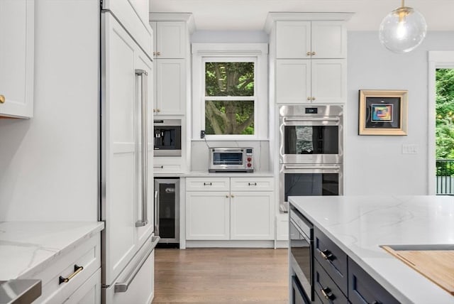 kitchen with white cabinets, light wood finished floors, beverage cooler, and built in appliances
