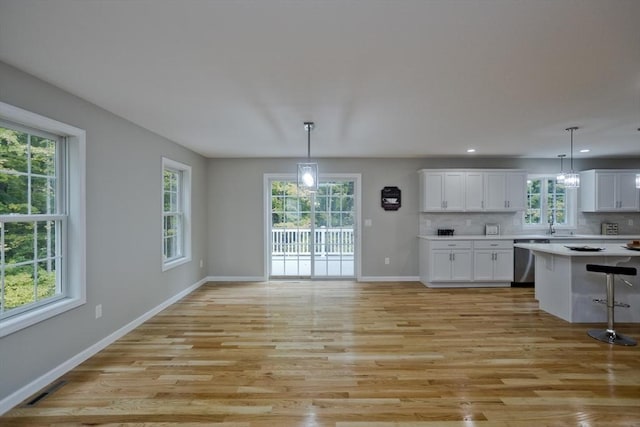 kitchen featuring tasteful backsplash, white cabinets, light countertops, and stainless steel dishwasher