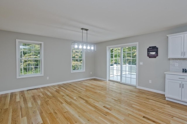 unfurnished dining area with light wood-type flooring and baseboards