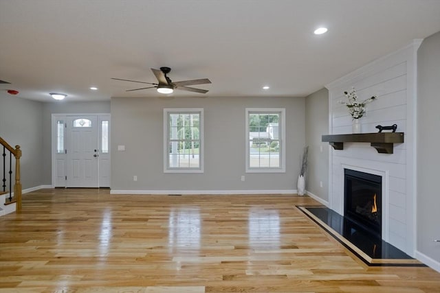 foyer with light wood-style floors, a fireplace, stairway, and baseboards