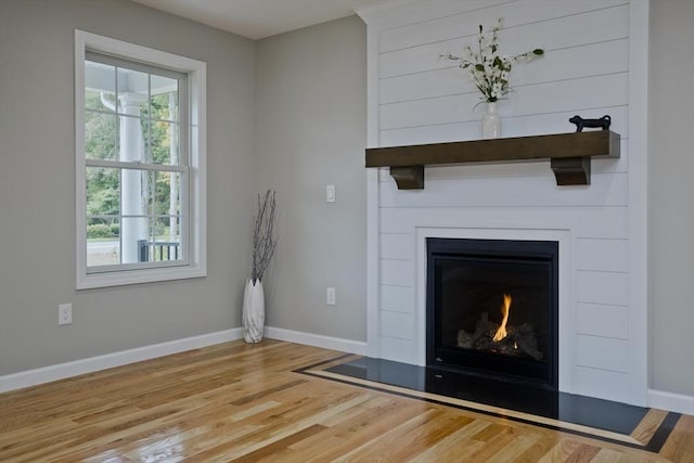 unfurnished living room with a fireplace, wood finished floors, and baseboards