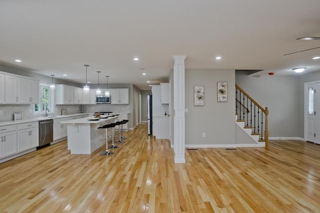 kitchen featuring stainless steel appliances, a breakfast bar, light countertops, and white cabinetry