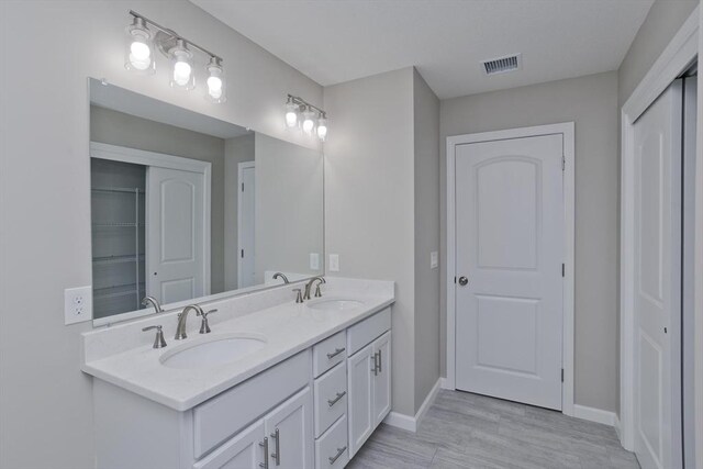 bathroom with visible vents, a sink, baseboards, and double vanity