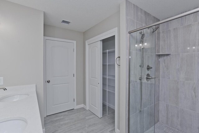 bathroom with wood finished floors, a stall shower, a sink, and visible vents