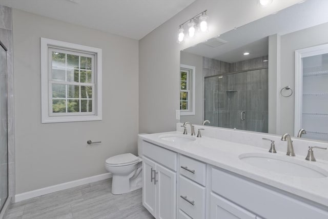 bathroom with toilet, a sink, a shower stall, and baseboards