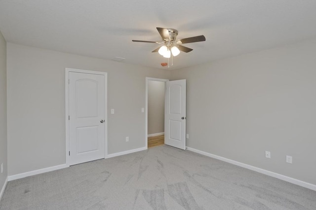 carpeted spare room featuring ceiling fan and baseboards