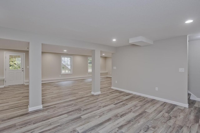 below grade area with light wood finished floors, recessed lighting, and baseboards