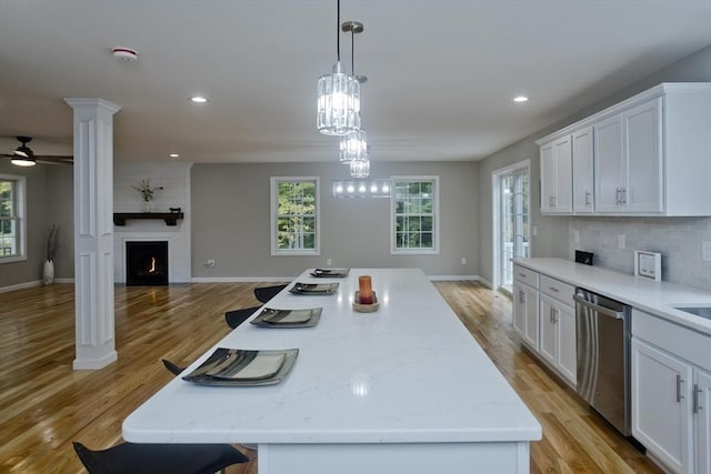 kitchen with white cabinets, decorative backsplash, open floor plan, and stainless steel dishwasher