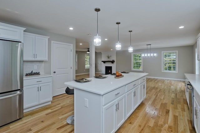 kitchen featuring stainless steel appliances, light countertops, white cabinetry, and light wood-style floors