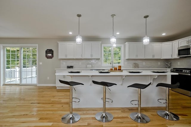 kitchen with white cabinetry, appliances with stainless steel finishes, light countertops, and decorative backsplash