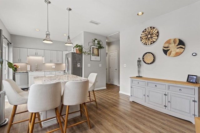 kitchen featuring stainless steel appliances, visible vents, decorative backsplash, a sink, and wood finished floors