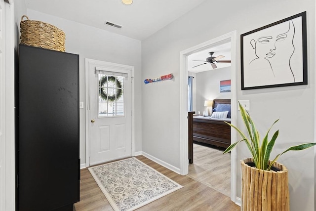 foyer entrance with baseboards, ceiling fan, visible vents, and light wood-style floors