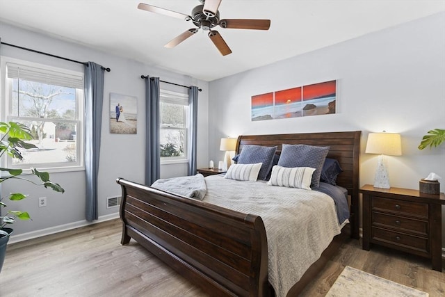 bedroom with a ceiling fan, visible vents, baseboards, and wood finished floors