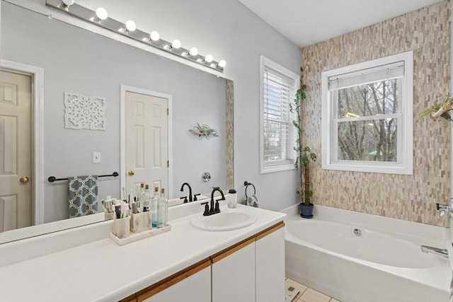 full bath featuring a garden tub, vanity, and tile patterned floors