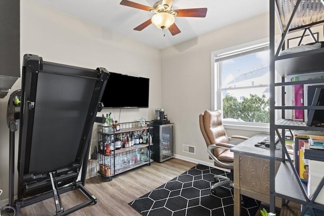 office with a ceiling fan, visible vents, baseboards, and wood finished floors