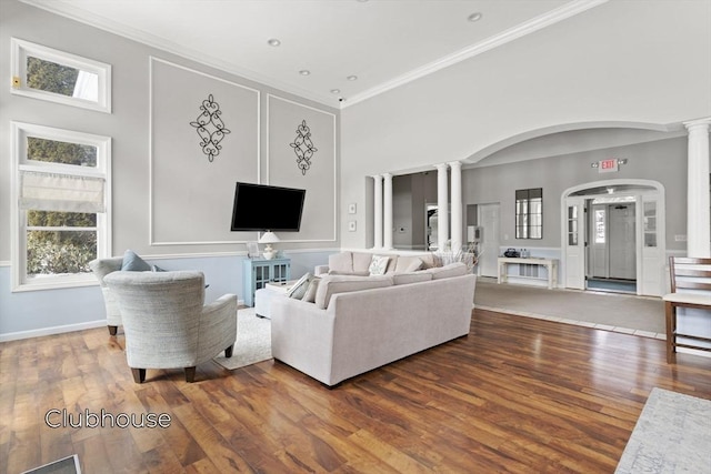 living area featuring arched walkways, wood finished floors, decorative columns, and crown molding