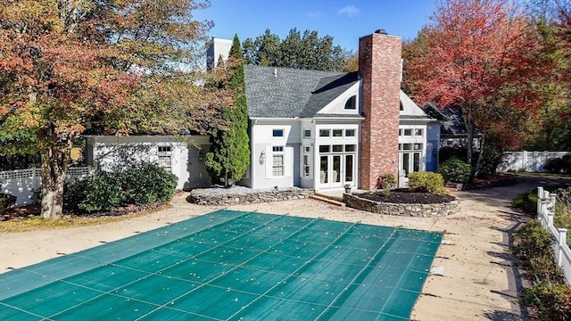 view of swimming pool with french doors, fence, and an outdoor structure