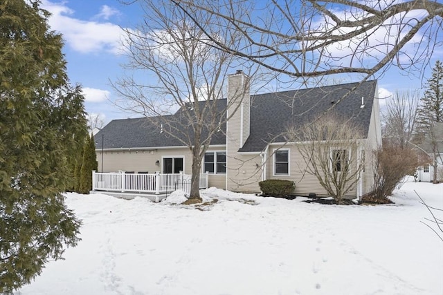 snow covered house featuring a chimney and a deck